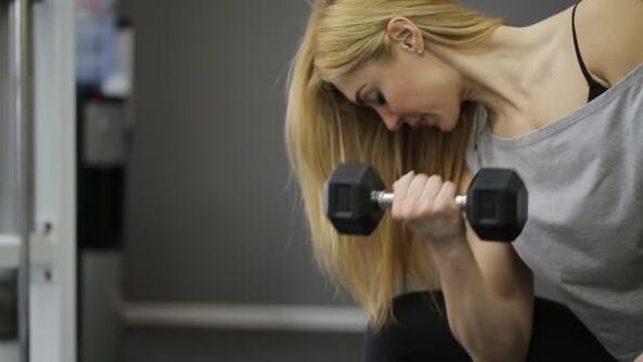 The girl performs a dumbbell exercise